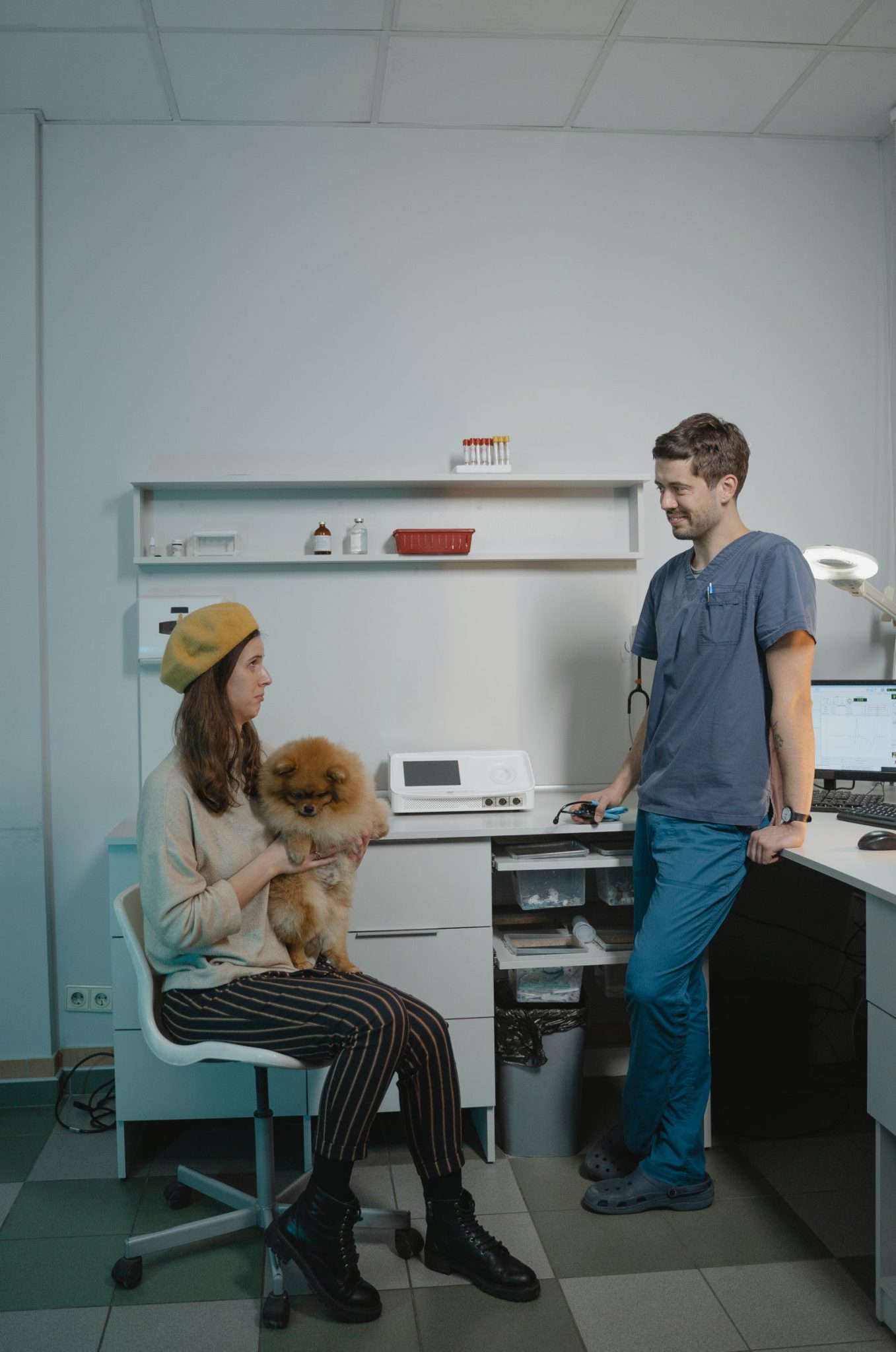 Vrouw met haar hond aan de balie van een dierenkliniek, het moment waarop de rekening en het eigen risico ter sprake komen.